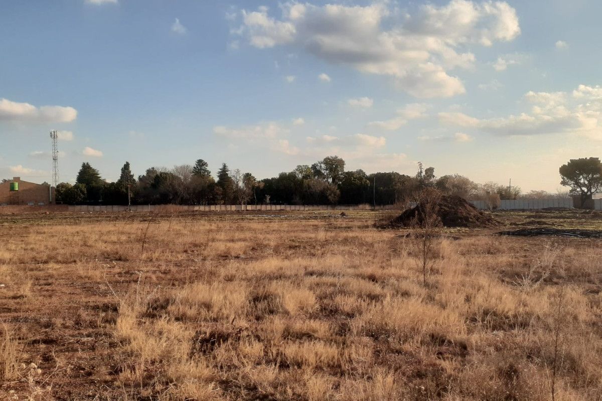 A large, undeveloped plot of land featuring dry grass and perimeter fencing, offering significant potential for future development or landscaping.