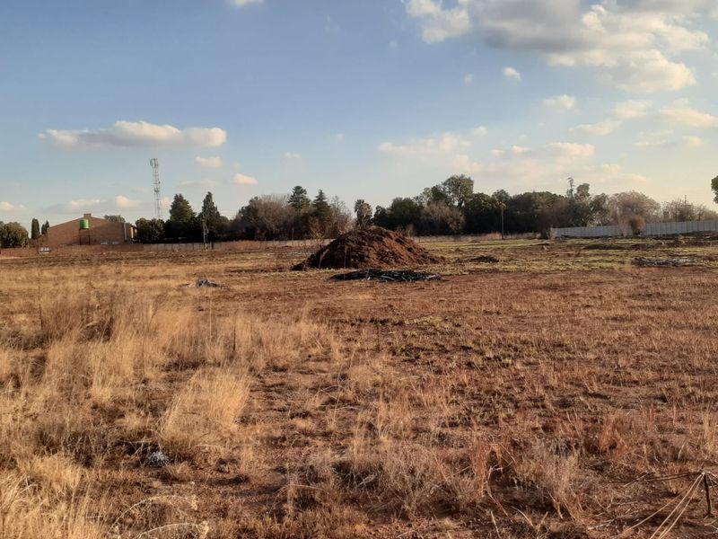 Expansive undeveloped land area featuring dry vegetation, a water tank in the distance, and perimeter fencing, suitable for agricultural or development purposes.