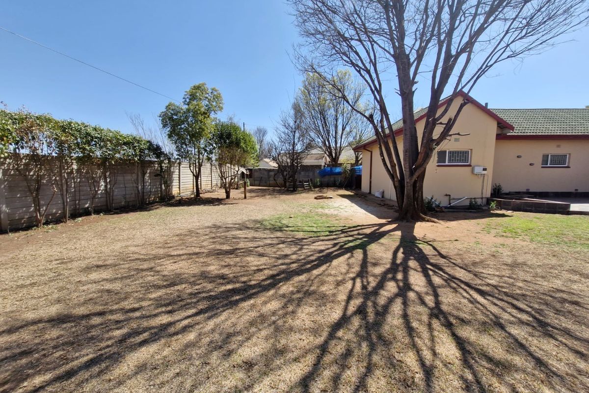 Spacious rear garden featuring a large mature tree, precast concrete boundary walls, and a view of the rear building elevation.