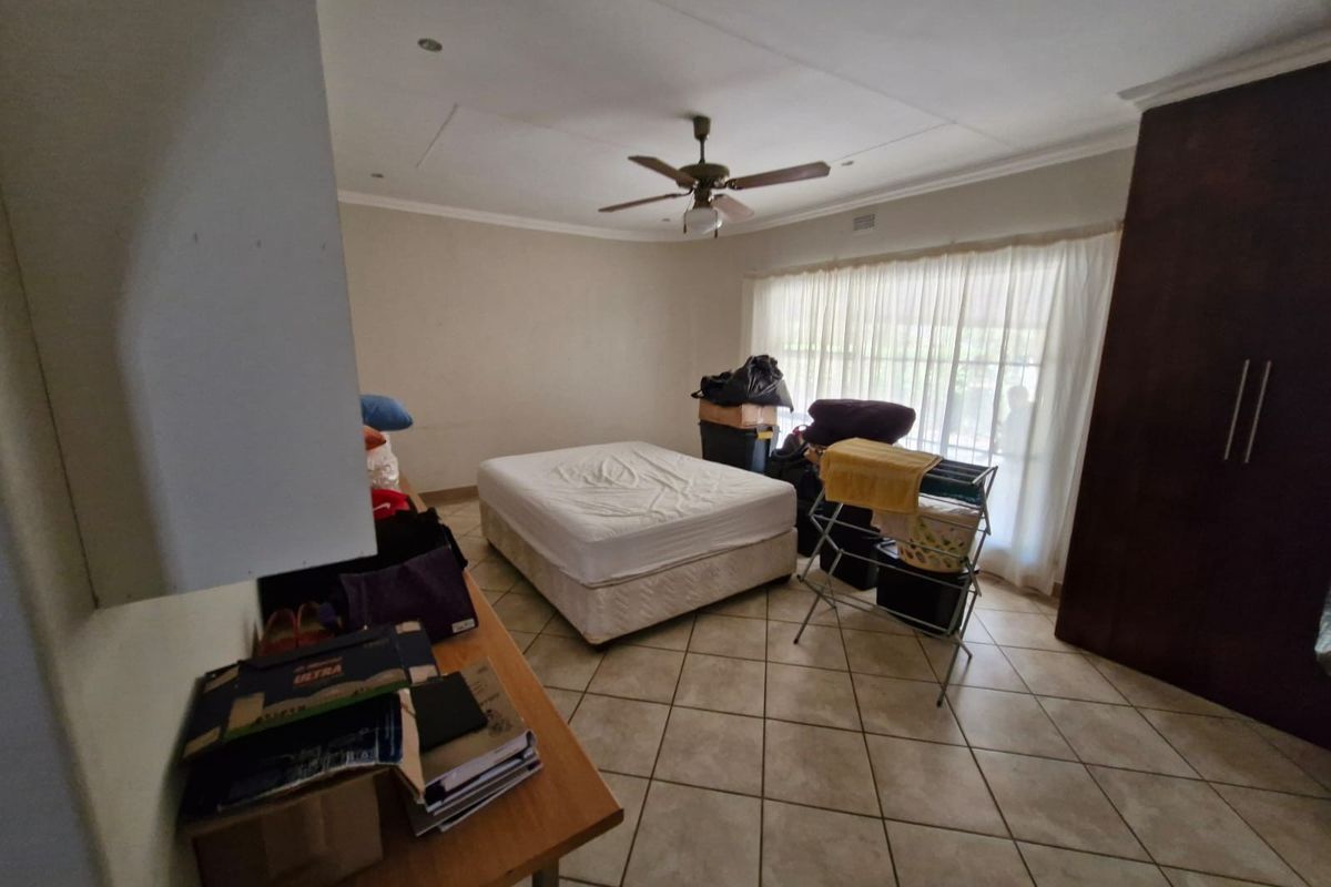 A bedroom featuring tiled flooring, built-in cupboards, and a ceiling fan, offering a functional space ready for personalization.