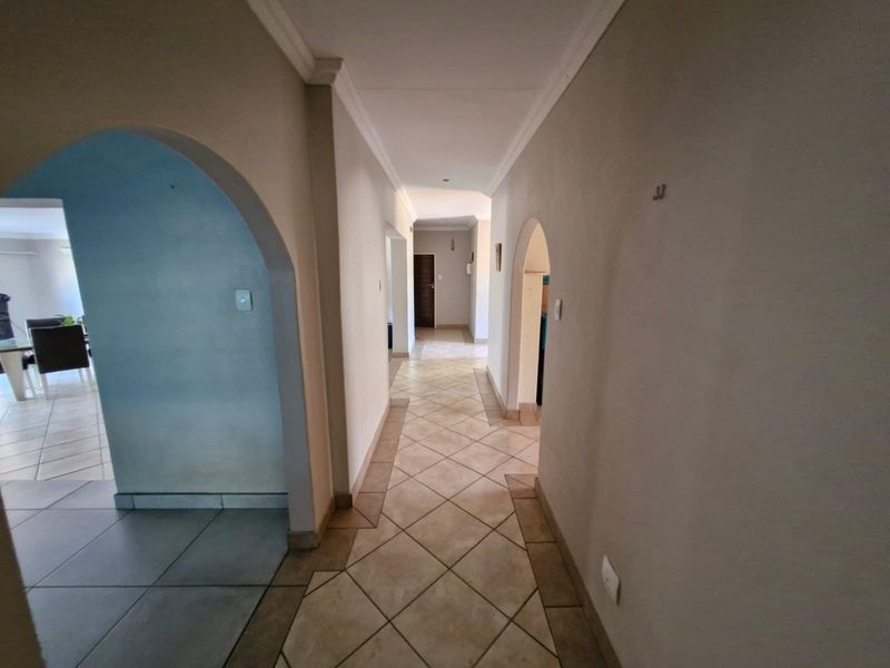 A spacious hallway featuring tiled flooring and architectural archways connecting to adjacent living areas.