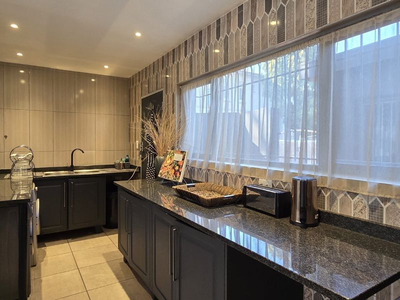 Modern kitchen featuring dark cabinetry, granite countertops, tiled backsplash, and recessed lighting, offering a functional and stylish workspace.