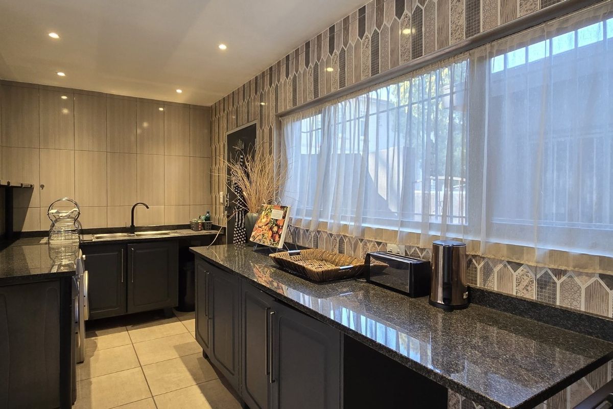 Modern kitchen featuring dark cabinetry, granite countertops, tiled backsplash, and recessed lighting, offering a functional and stylish workspace.
