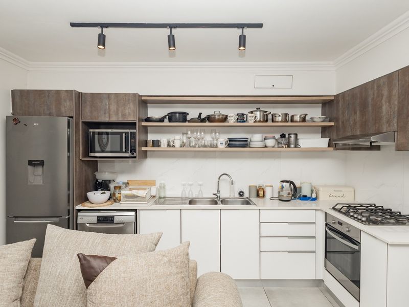 Modern kitchen featuring sleek white cabinetry, stone-look countertops, integrated gas cooktop, built-in oven, and open shelving for convenient storage.