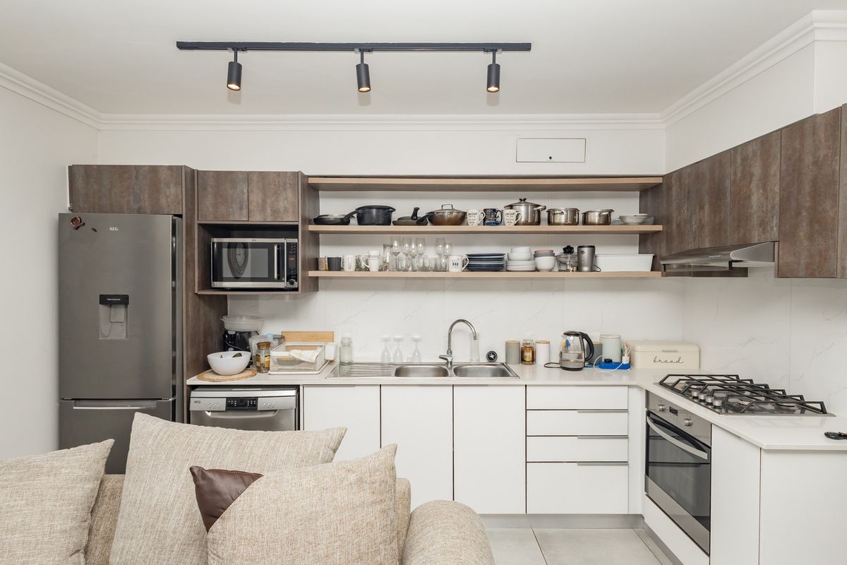 Modern kitchen featuring sleek white cabinetry, stone-look countertops, integrated gas cooktop, built-in oven, and open shelving for convenient storage.