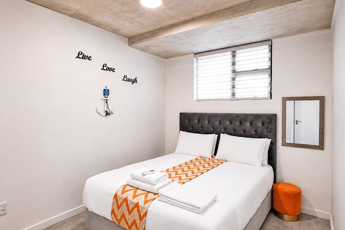 A compact bedroom featuring tiled flooring, a recessed ceiling detail, and venetian blinds, providing a clean and functional sleeping space.