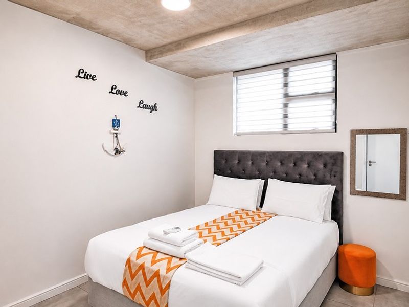 A compact bedroom featuring tiled flooring, a recessed ceiling detail, and venetian blinds, providing a clean and functional sleeping space.