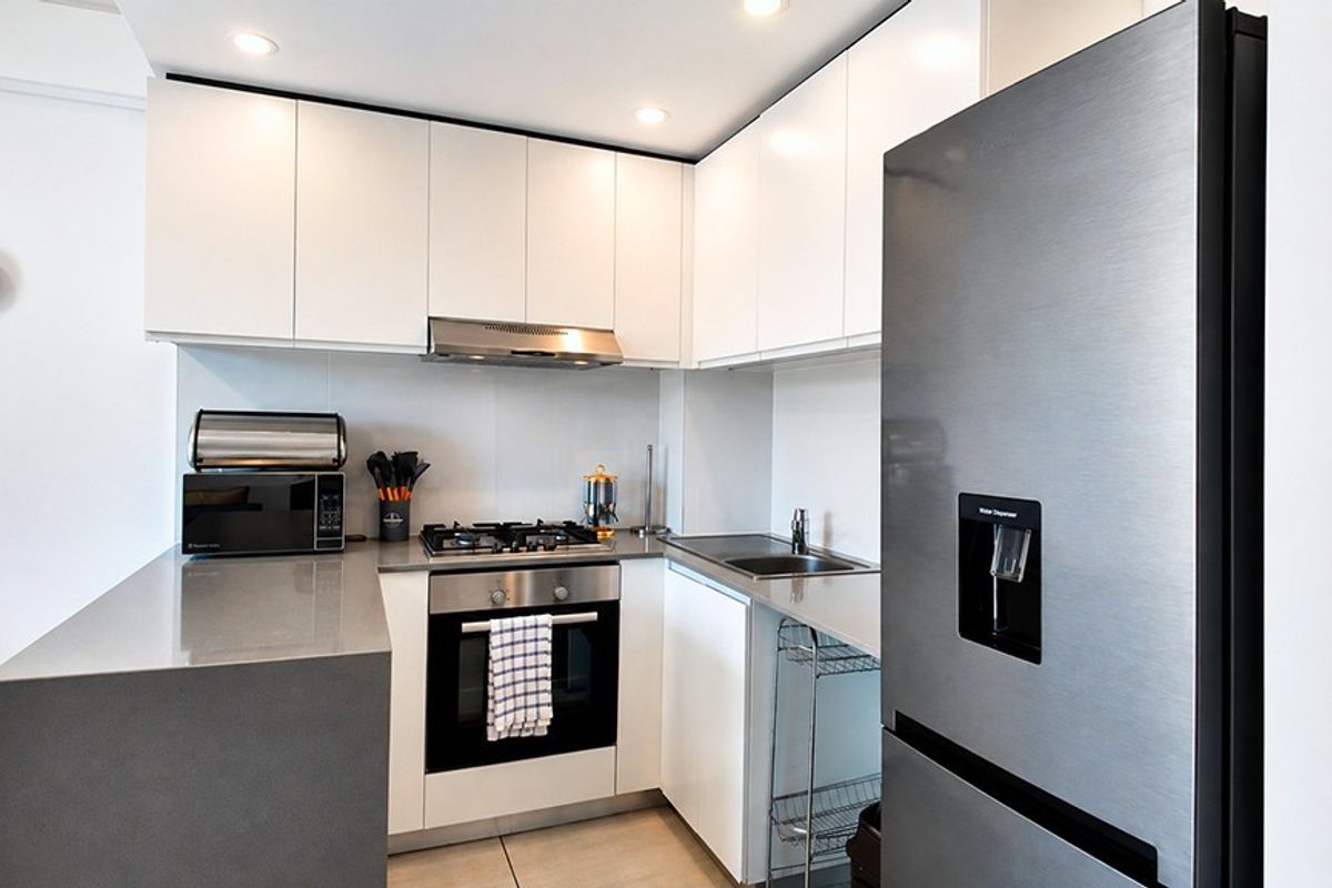 Modern kitchen featuring white cabinetry, stone countertops, stainless steel appliances, gas hob, and built-in oven with recessed lighting.