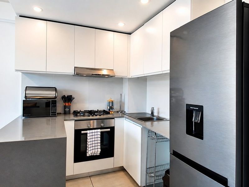 Modern kitchen featuring white cabinetry, stone countertops, stainless steel appliances, gas hob, and built-in oven with recessed lighting.