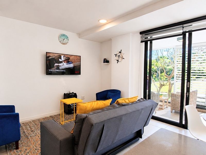 Bright open-plan living area featuring tiled floors, recessed lighting, and large sliding glass doors providing seamless access to the outdoor patio space.