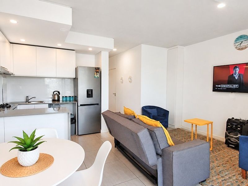 Modern open-plan living area featuring a sleek kitchen with stone countertops, ample cabinetry, and tiled flooring, seamlessly flowing into the lounge space.
