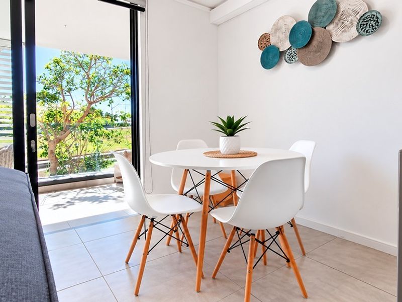 Bright living area featuring large sliding glass doors that open onto a balcony, complemented by neutral tiled flooring.