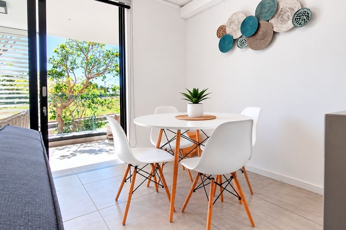Bright living area featuring large sliding glass doors that open onto a balcony, complemented by neutral tiled flooring.