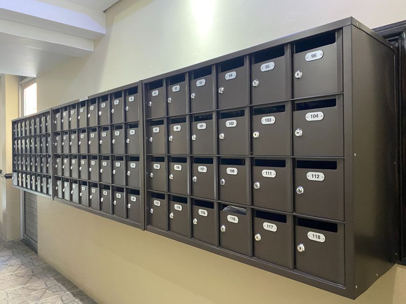 A wall-mounted bank of numbered metal mailboxes located in the apartment building entrance area.