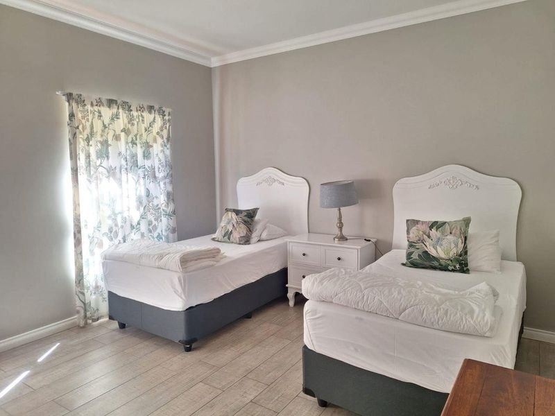 A well-maintained bedroom featuring neutral wall tones, crown molding, and durable tiled flooring.