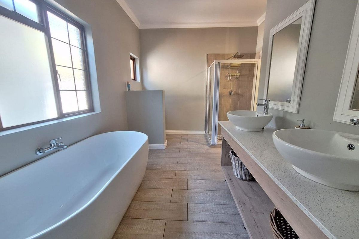 Modern bathroom featuring a freestanding bathtub, double vanity with vessel sinks, and a separate walk-in shower with neutral tiled finishes.