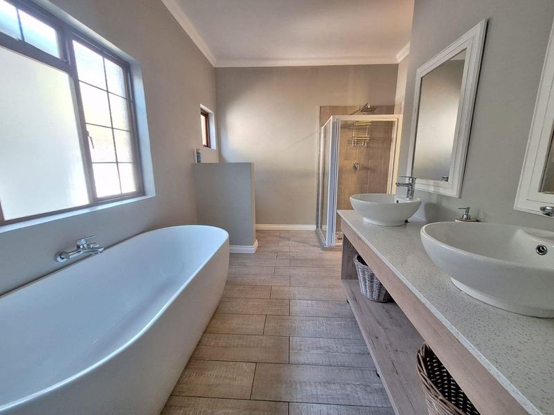 Modern bathroom featuring a freestanding bathtub, double vanity with vessel sinks, and a separate walk-in shower with neutral tiled finishes.