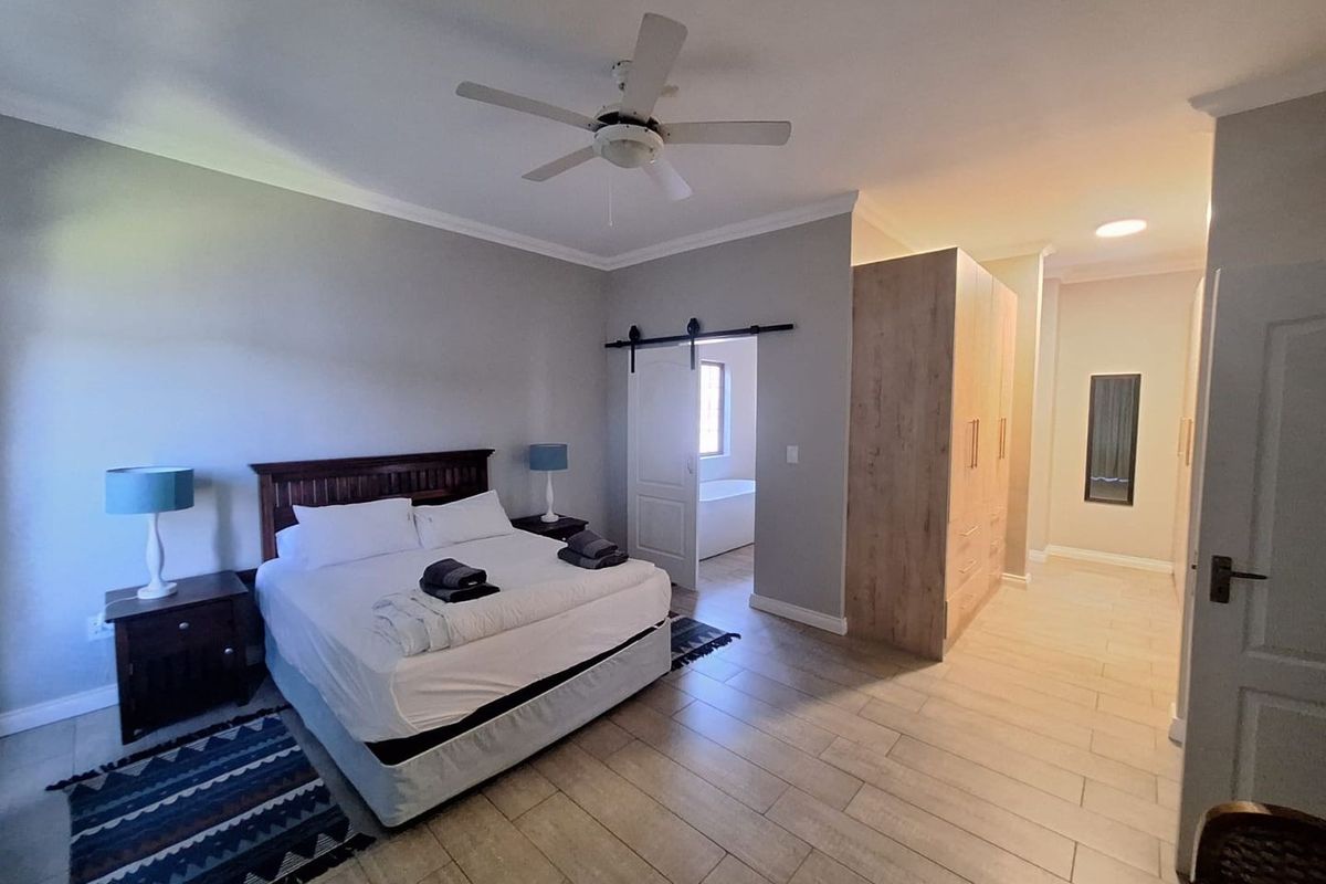 Spacious bedroom featuring tiled flooring, a ceiling fan, built-in wardrobe, and a sliding barn door leading to an en-suite bathroom.