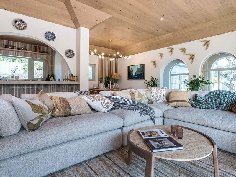 Spacious open-plan living area featuring a striking timber-clad vaulted ceiling, arched architectural details, and a seamless transition to the kitchen space.