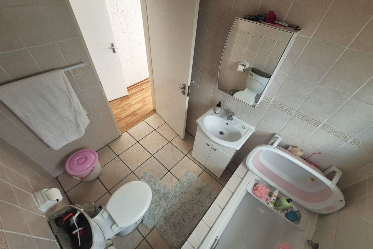 A functional bathroom featuring ceramic tiling, a vanity with basin, a toilet, and a bathtub, providing essential sanitary facilities for the apartment.