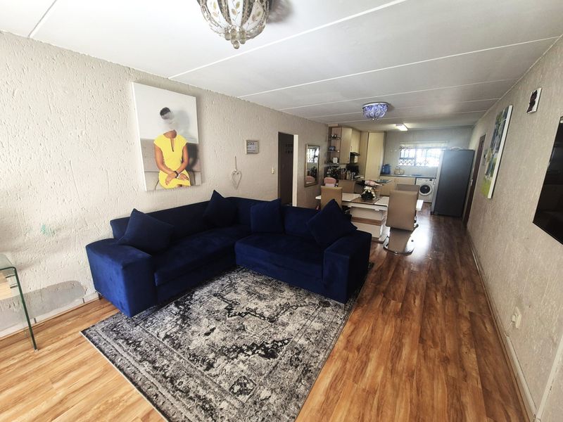 Open-plan living and kitchen area featuring laminate flooring, textured walls, and functional built-in cabinetry, offering a versatile space for daily living.