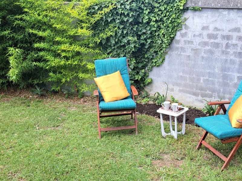 A private garden area featuring a lawn and a concrete block boundary wall with climbing ivy.