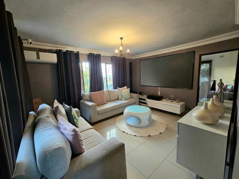 A comfortable living room featuring tiled flooring, crown molding, and a wall-mounted air conditioning unit.