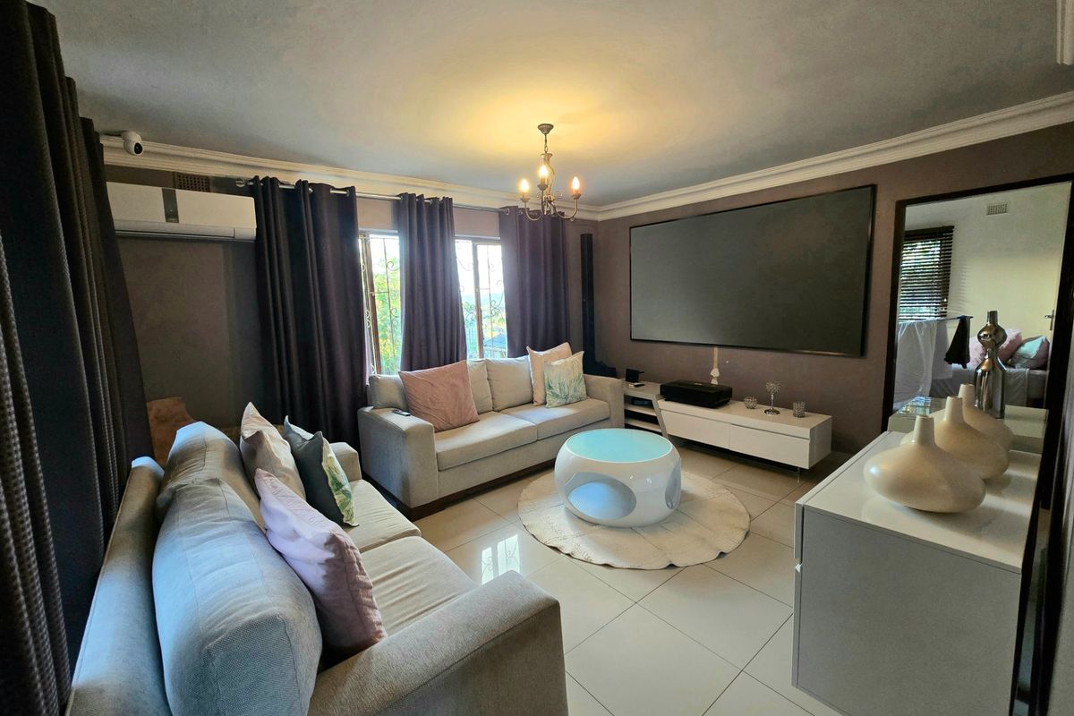 A comfortable living room featuring tiled flooring, crown molding, and a wall-mounted air conditioning unit.
