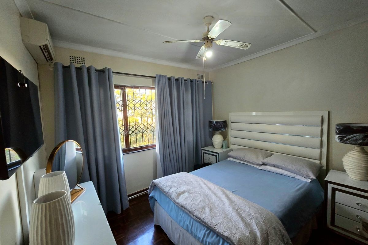 A well-maintained bedroom featuring parquet flooring, a ceiling fan, and an integrated air conditioning unit.