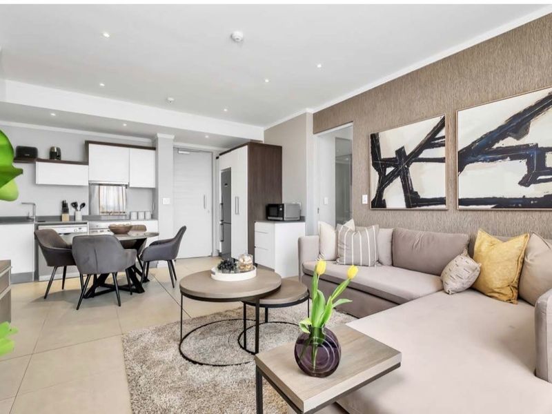 Modern open-plan living area featuring a sleek kitchen with built-in cabinetry, tiled floors, and a stylish textured feature wall.