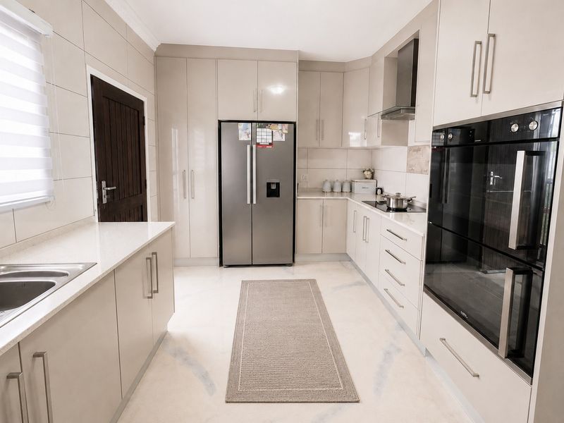 Modern kitchen featuring high-gloss cabinetry, quartz countertops, integrated stainless steel appliances, and sleek tiled finishes throughout.