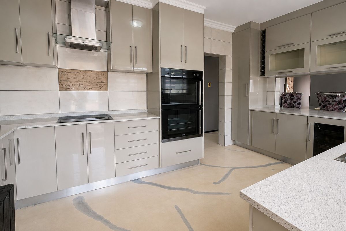Modern kitchen featuring high-gloss cabinetry, quartz countertops, integrated double wall oven, electric hob, and a stylish tiled backsplash.