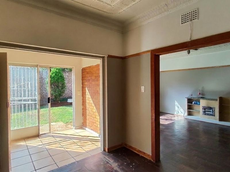 Spacious living area featuring parquet flooring, decorative ceilings, and direct access to a tiled patio area through sliding glass doors.