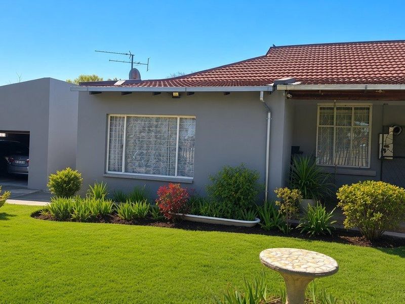 Front view of a well-maintained house featuring a tiled roof, attached garage, and a neat front garden with a paved driveway.