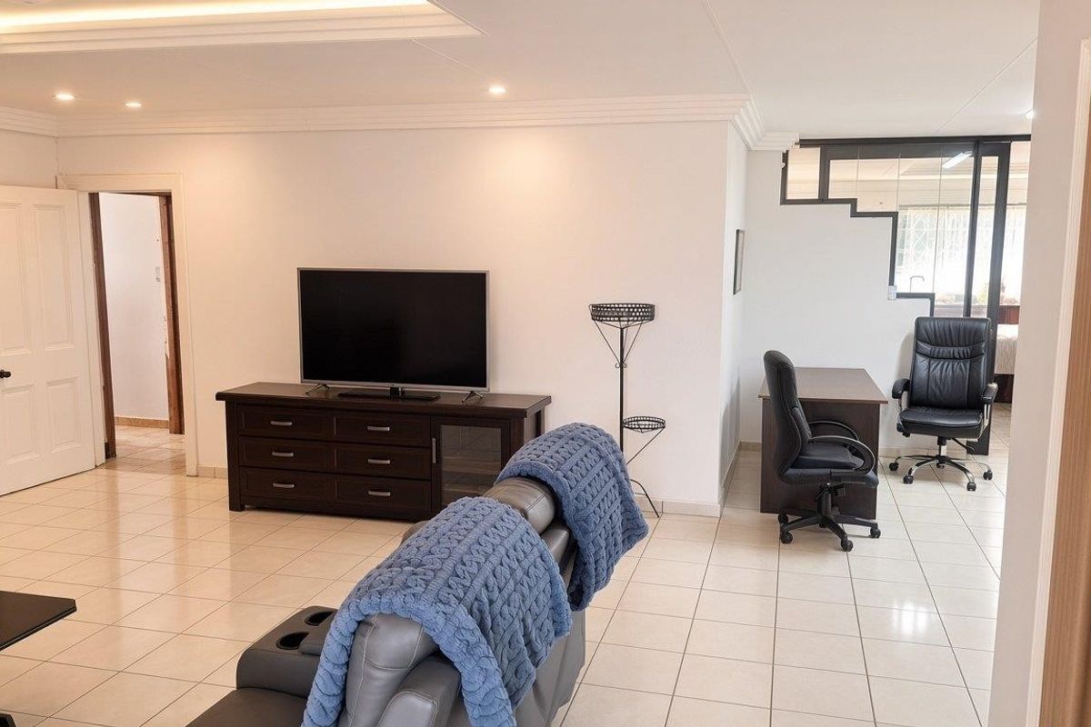 Spacious living area featuring neutral tiled flooring, recessed ceiling lighting, and coved cornicing, providing a versatile open-plan layout.
