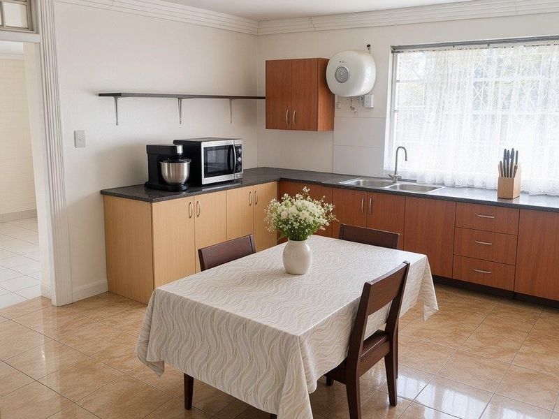 A functional kitchen featuring laminate cabinetry, dark countertops, a double bowl sink, and ceramic floor tiles, offering a practical layout for daily use.