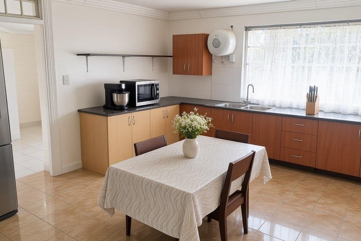A functional kitchen featuring laminate cabinetry, dark countertops, a double bowl sink, and ceramic floor tiles, offering a practical layout for daily use.