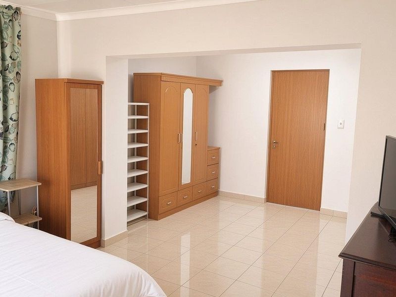 A bedroom featuring tiled flooring and a neutral color palette, providing a functional space with a built-in door and coved ceiling details.