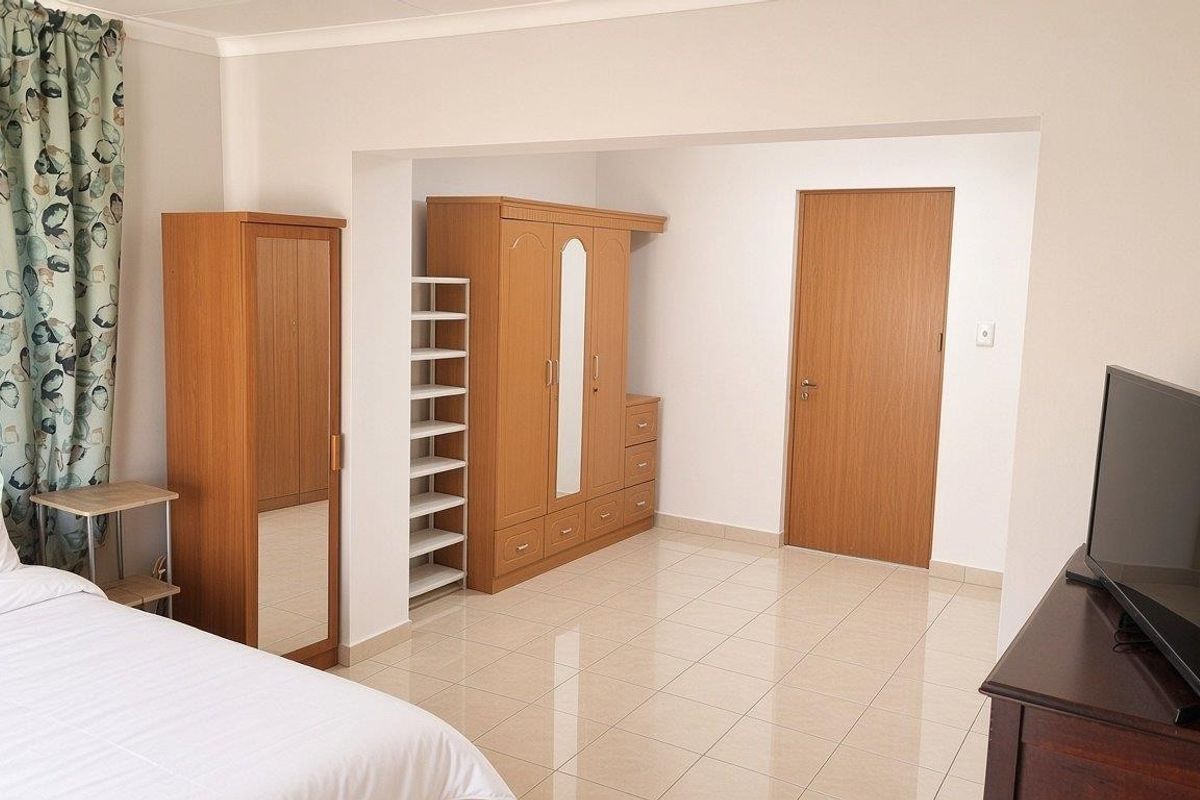 A bedroom featuring tiled flooring and a neutral color palette, providing a functional space with a built-in door and coved ceiling details.