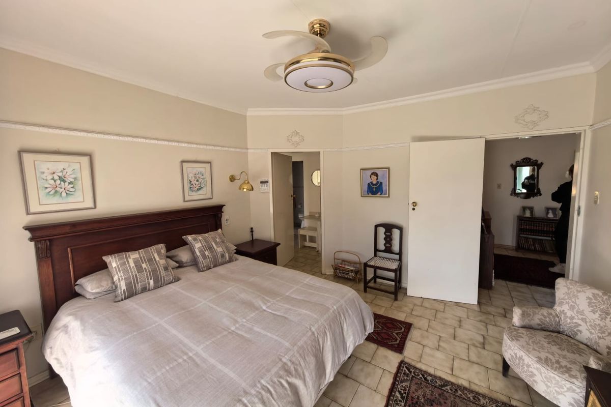 Spacious bedroom featuring tiled flooring, decorative coving, picture rails, and a central ceiling fan, with direct access to an adjoining room.