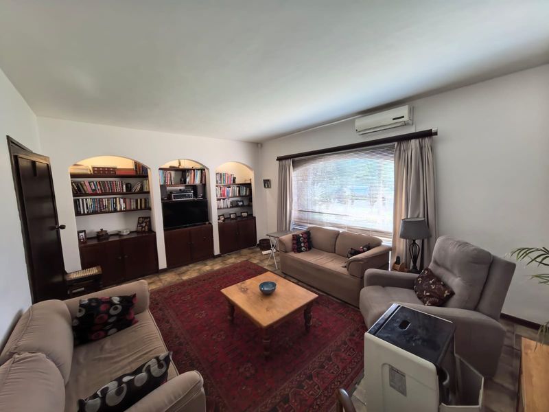 A comfortable living room featuring built-in arched shelving, cabinetry, and a split-system air conditioner, providing a functional and well-maintained space.