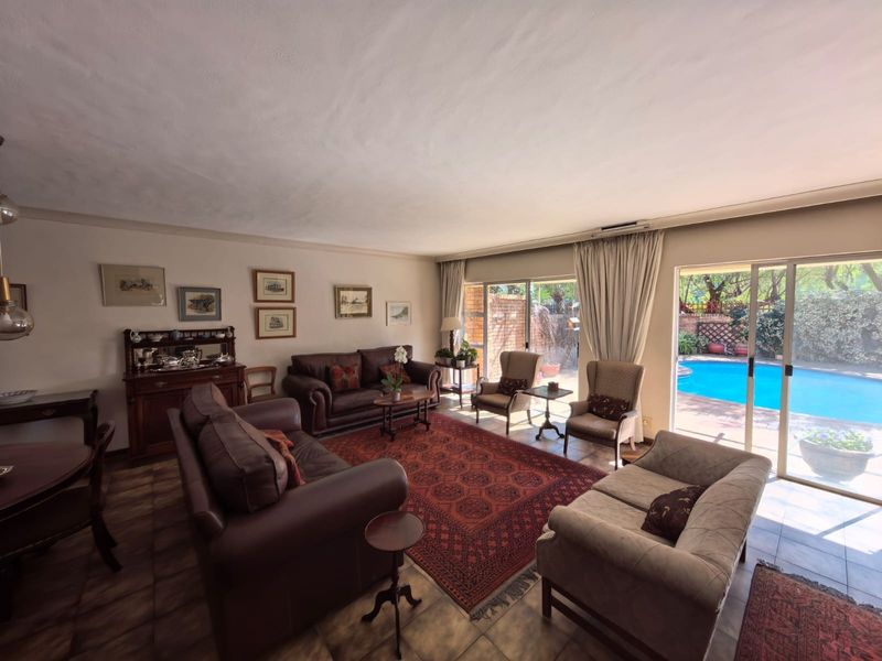Spacious living room featuring tiled flooring and large sliding glass doors that provide direct access to the outdoor pool area.
