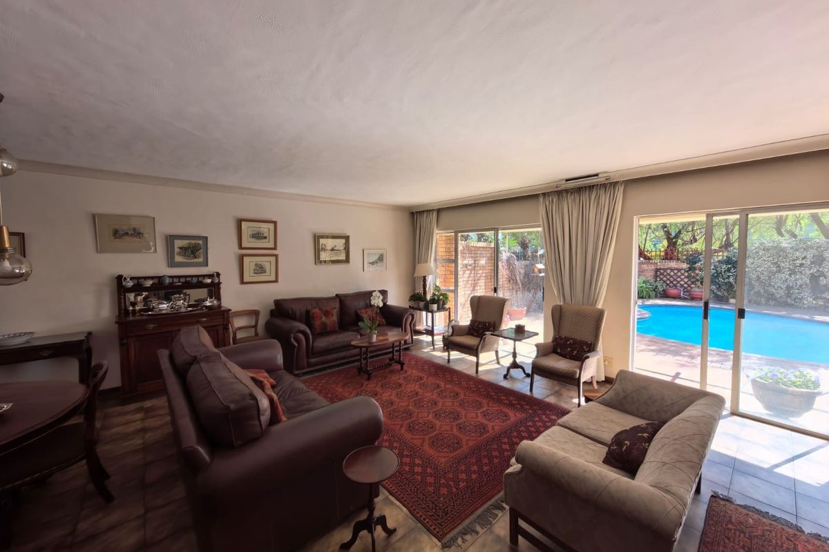 Spacious living room featuring tiled flooring and large sliding glass doors that provide direct access to the outdoor pool area.
