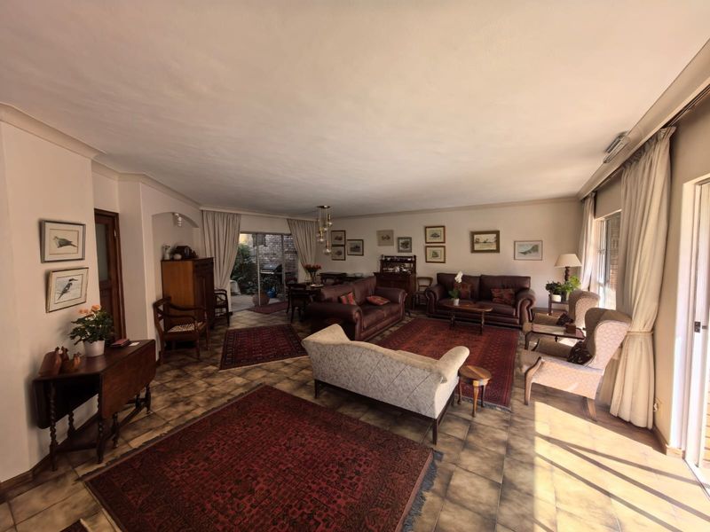 Spacious open-plan living and dining area featuring tiled flooring, coved cornicing, and large sliding glass doors providing access to the outdoor patio.