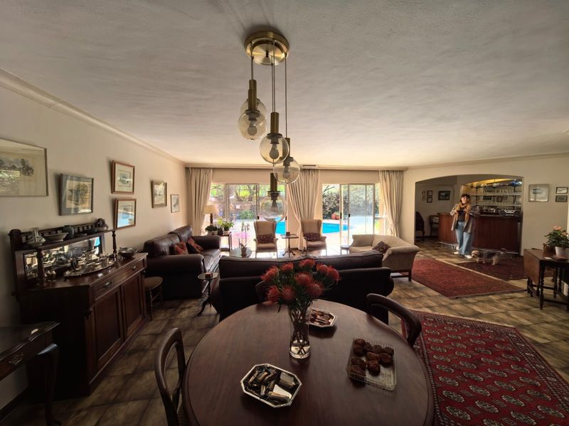 Spacious open-plan living and dining area featuring tiled floors, a built-in bar, and sliding glass doors leading to the pool area.