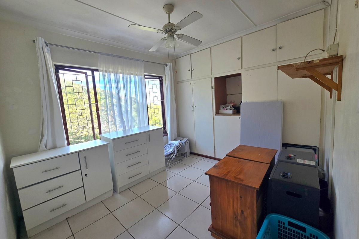 Bedroom featuring tiled flooring, built-in cupboards, and a ceiling fan, with security bars on the windows.
