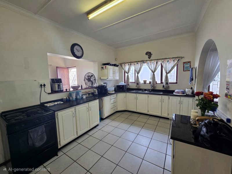 A functional kitchen featuring white cabinetry, dark granite countertops, ceramic tile flooring, and a convenient pass-through window to the adjacent living area.