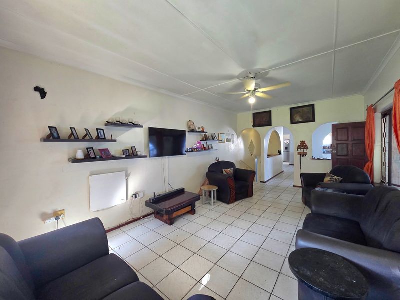Spacious living room featuring ceramic floor tiles, a ceiling fan, and distinctive archways leading to adjacent areas of the home.