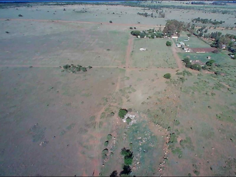 Aerial view of a large farm property featuring open grazing land, dirt access roads, and a cluster of outbuildings.