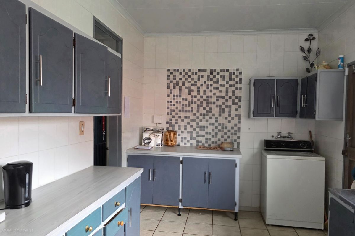 A functional kitchen featuring built-in cabinetry, tiled splashbacks, and tiled flooring, offering a practical layout with potential for modern cosmetic updates.